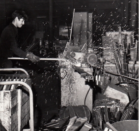 Czarno-białe zdjęcie pracownika obrabiającego półkę w latach 70. XX wieku
			