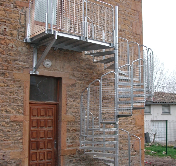 Stalowe schody spiralne zapewniające dostęp z zewnątrz na 1. piętro budynku
					                    