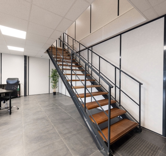 Metalowe schody z drewnianymi stopniami zainstalowane w pomieszczeniach biznesowych w celu zapewnienia dostępu na wyższe piętro
		                    